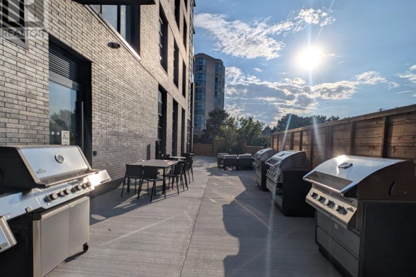 BBQ area featuring multiple stainless steel grills and seating under a sunny sky. - 323c - 1612 Charles Street, Whitby