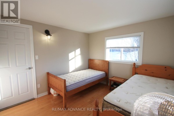 Bedroom featuring two twin beds, light beige walls, a closed white door, and a window with sunlight. - 323d Grahamvale Road, Chisholm