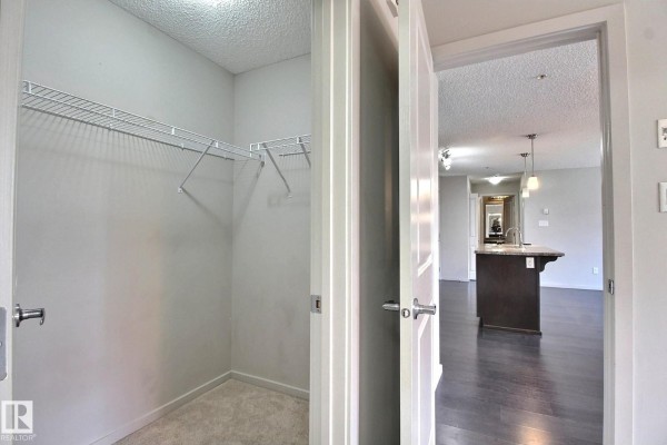 Dining area with dark wood floors, neutral walls, and sliding doors to a balcony. - #324 344 Windermere Rd Nw, Edmonton