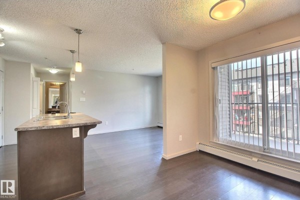 Kitchen with a large island, dark brown cabinets, stainless steel appliances, and laundry closet. - #324 344 Windermere Rd Nw, Edmonton