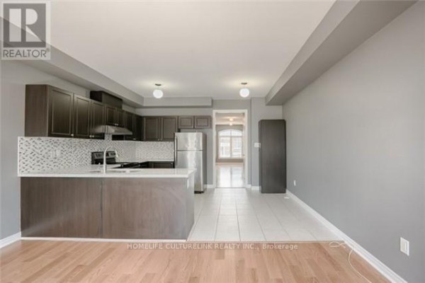 Kitchen and living area with dark wood cabinets, stainless steel appliances, white countertops, and light wood floors. - 324 Delray Drive, Markham