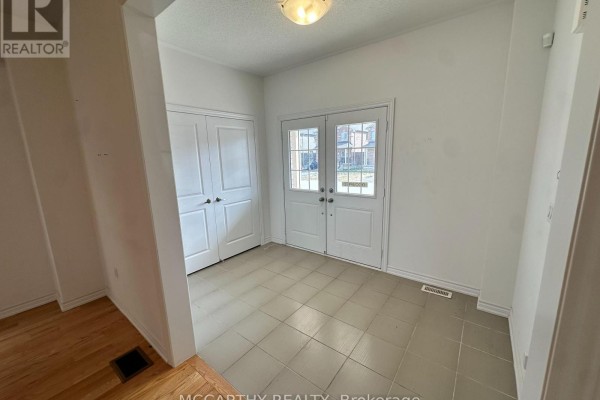 Interior foyer with beige tiled floor, white walls, double front doors, and closet. - 324 Moody Street, Southgate