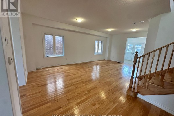 Living room with hardwood floors, white walls, and a view of the staircase. - 324 Moody Street, Southgate