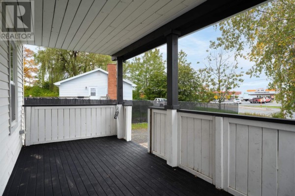 Side exterior view of the white clapboard house with a sloping green lawn and trees. - 324 Wentworth Road, Windsor