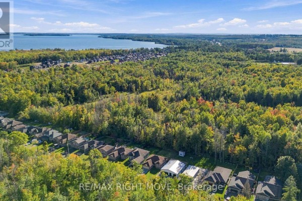 Aerial view of a wooded landscape with houses, showing a lake and residential development. - 3240 Goldstein Road, Severn