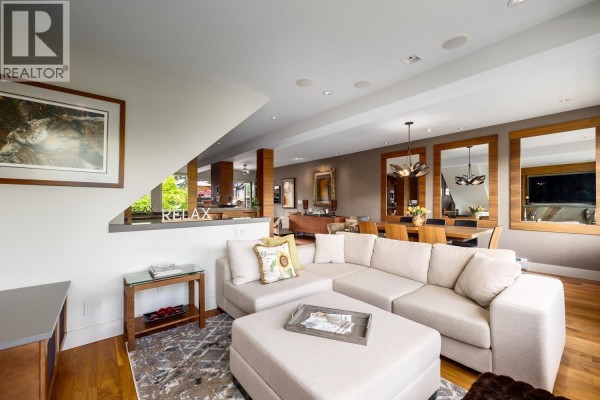Living room with a sectional sofa, large television, and gas fireplace. - 3240 W 1st Avenue, Vancouver