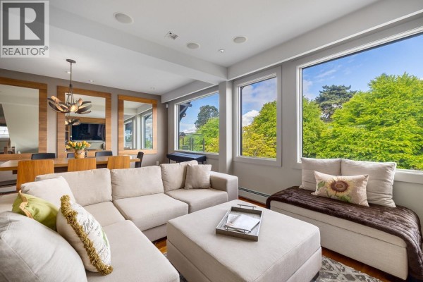 Living room with a large window, sofa, fireplace, and built-in shelving. - 3240 W 1st Avenue, Vancouver