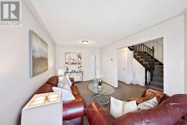 Living room with leather sofa, glass coffee table, and staircase - 3242 Tortola Court Mississauga