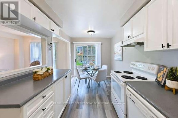 Kitchen and dining area with white cabinets, glass table, and backyard access - 3242 Tortola Court Mississauga