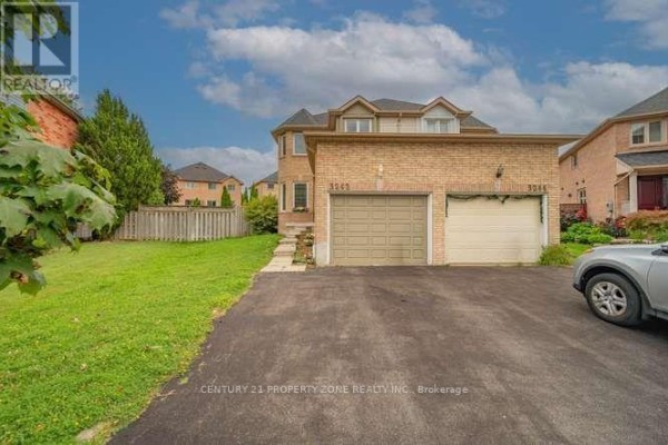 View of the right side of a brick house with a double garage and green lawn. - 3242 Tortola Court, Mississauga