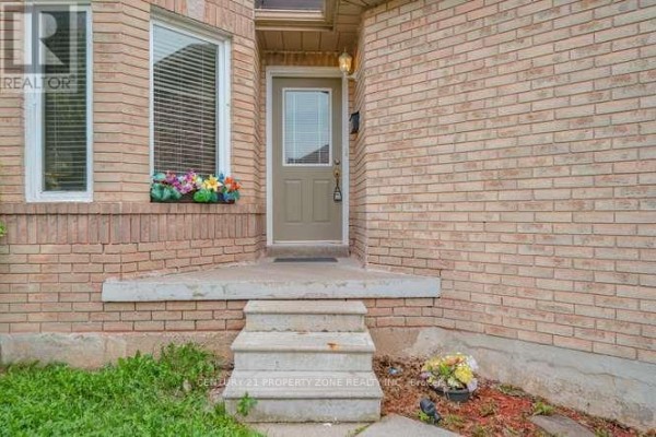 Close-up of the front door of a brick house with concrete steps and window planter. - 3242 Tortola Court, Mississauga