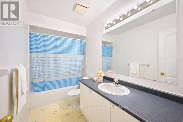 Bathroom with vanity, sink, large mirror, toilet, and tub with blue shower curtain - 3242 Tortola Court Mississauga