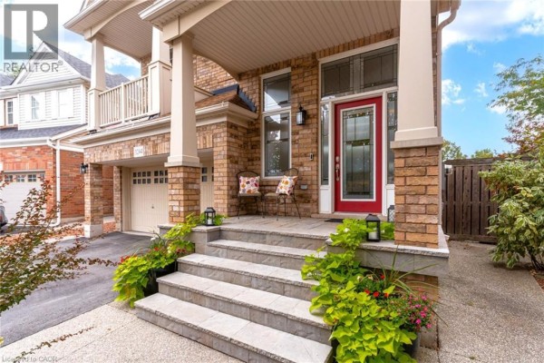 Front porch steps with stone risers and planters, leading to a red front door. - 3244 Steeplechase Drive, Burlington