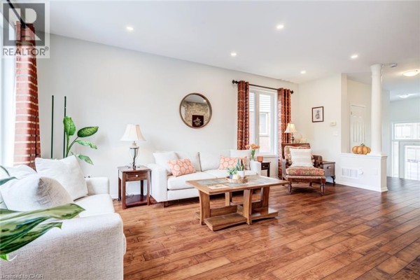 Living room with white sofas, a coffee table, a decorative mirror, and hardwood floors. - 3244 Steeplechase Drive, Burlington