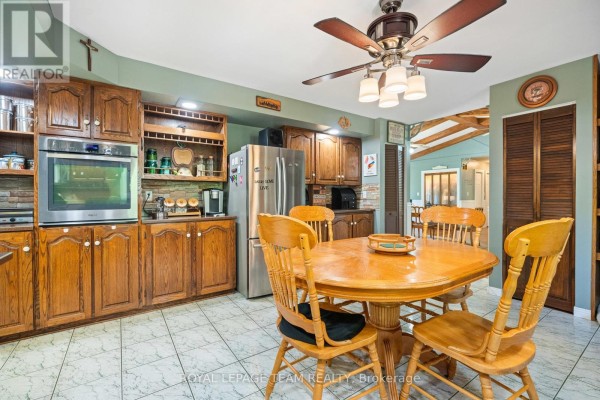 Kitchen with wooden cabinets, stainless steel refrigerator, and dining table. - 3245 Wallace Road, North Dundas