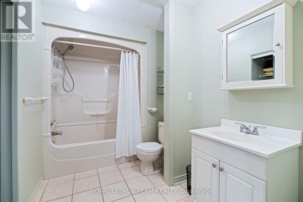 Bathroom with white vanity, toilet, and bathtub with shower curtain. - 3245 Wallace Road, North Dundas