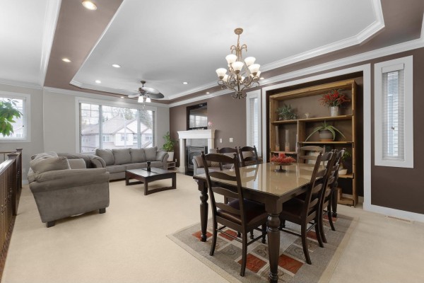 Living and dining area with fireplace, sofa, dining table, and large windows. - 32460 Mitchell Avenue, Mission