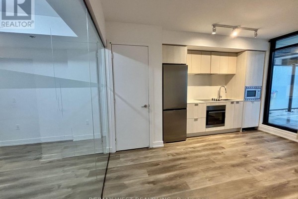 Open concept studio apartment with a kitchen, stainless steel fridge and wood floors. - 325 - 1 Jarvis Street, Hamilton