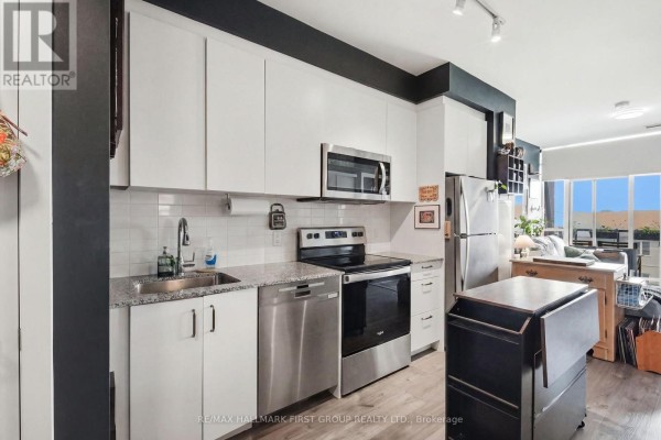 Kitchen with white cabinets, stainless steel appliances, a subway tile backsplash, and a view of the living room. - 325 - 1010 Dundas St E Street, Whitby