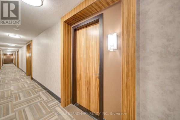 Hallway of an apartment building with wood-paneled walls, grey carpet, and unit door 325. - 325 - 50 Clegg Road, Markham