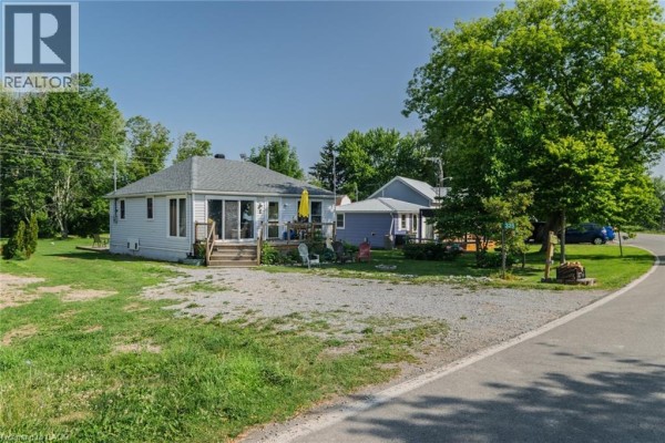 Front exterior of 325 Blue Water Parkway, a light blue cottage with a deck and lawn. - 325 Blue Water Parkway, Selkirk