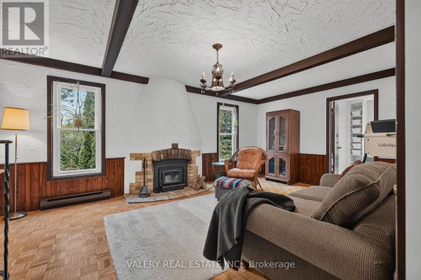 Living room with a brick fireplace, wood-paneled walls, parquet flooring, a sofa, and a large window. - 325 Coleridge Drive, Waterloo