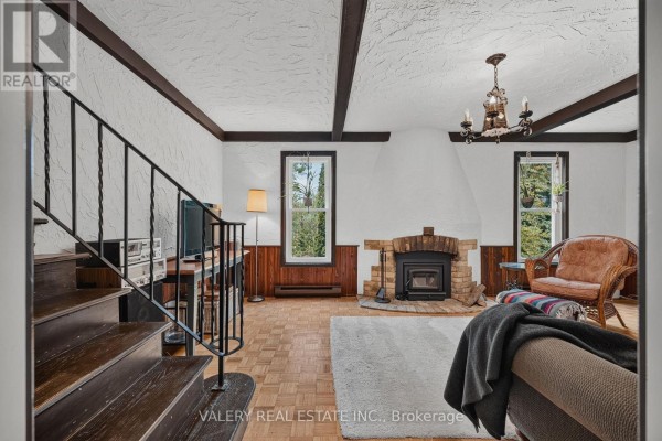 Living room with a fireplace, sofa, armchair, wood-paneled walls, parquet flooring, and a view of the stairs. - 325 Coleridge Drive, Waterloo
