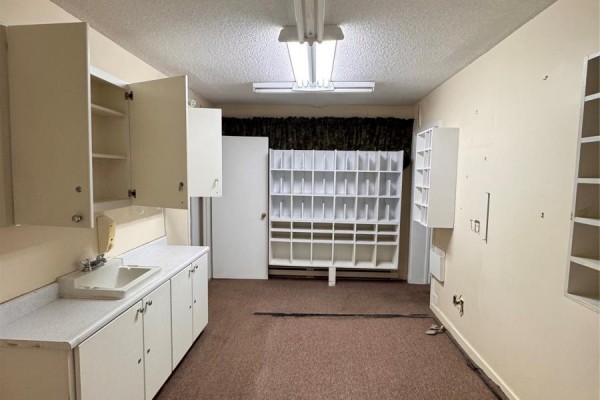 Room with a U-shaped counter, sink, cabinetry, a door, and multiple rows of shelving units. - 325 Hamilton Avenue, St  John S