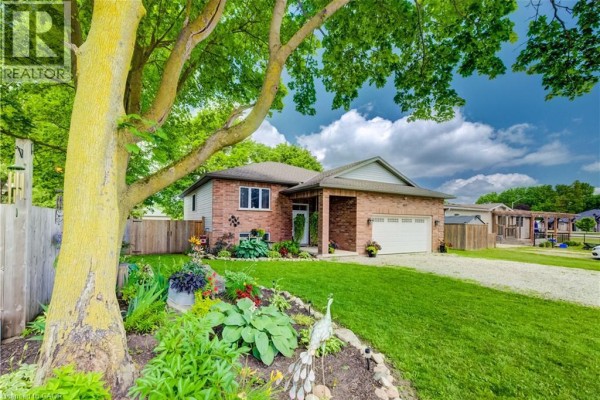 Exterior view of a red brick bungalow with a large tree in the foreground. - 325 Mill Street, Palmerston