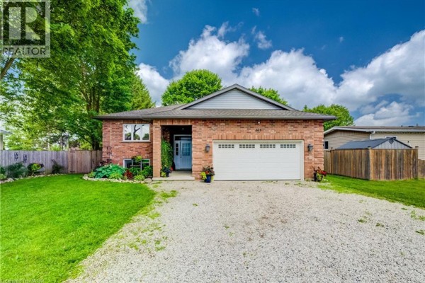 Red brick bungalow with a white garage door and a gravel driveway on a sunny day. - 325 Mill Street, Palmerston