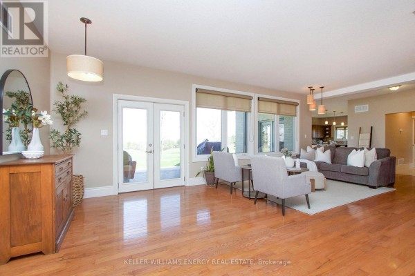 Spacious living room with hardwood floors, large windows, double doors to yard, and sectional sofa. - 325 Zion Line, Cavan Monaghan