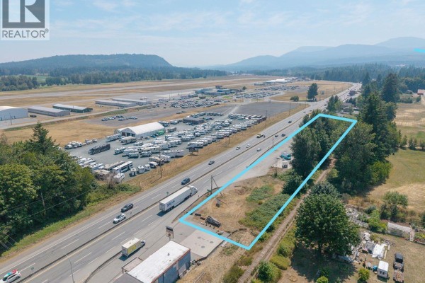 Long aerial view of the property lot outlined in blue, adjacent to the highway and an airport. - 3251 Trans Canada Hwy, Nanaimo