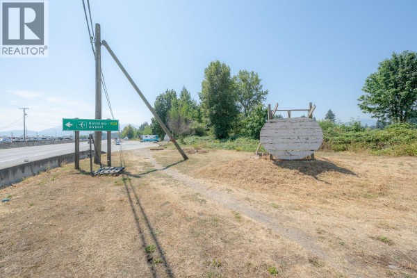 Paved area with a DOMO gas station sign, concrete barriers, and trees under a blue sky. - 3251 Trans Canada Hwy, Nanaimo