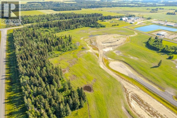 Aerial view looking over a large, partially cleared lot with a dense treeline and highway. - 32532,  Range Road 42, Rural Mountain View County