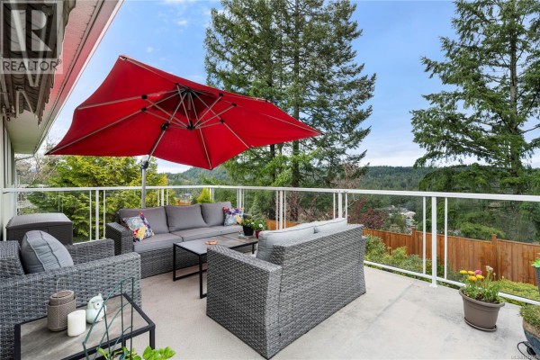 View of the back of the townhouse from a green, mossy slope. - 3255 Folkestone Dr, Nanaimo