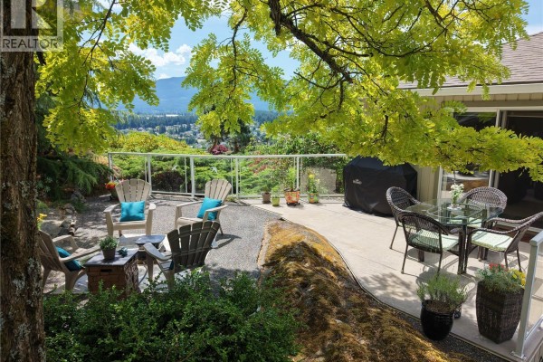 Aerial view of the multi-level back deck with glass railings and surrounding trees. - 3255 Folkestone Dr, Nanaimo