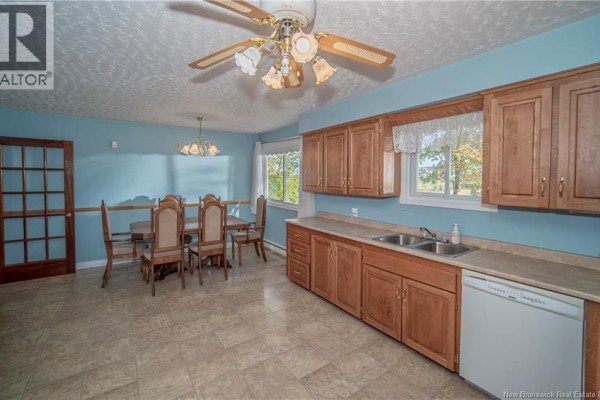 Kitchen and dining area with wood cabinets, light blue walls, and tiled floor. - 3259 Route 148, Nashwaak Bridge