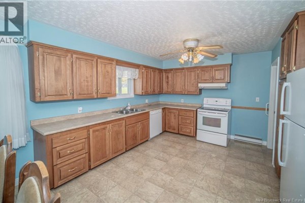 L-shaped kitchen with wood cabinets, beige countertops, and white appliances. - 3259 Route 148, Nashwaak Bridge