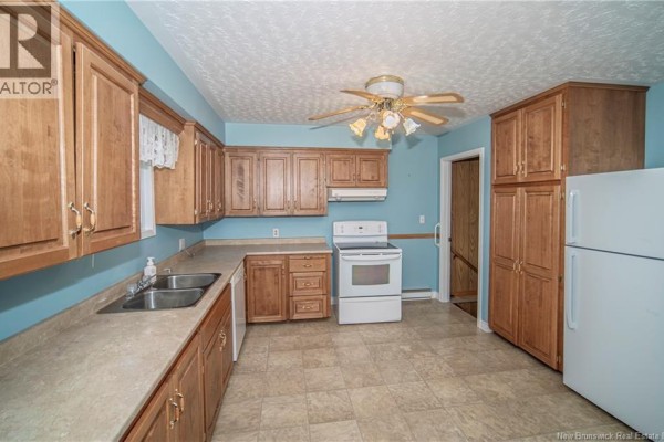 Kitchen with wood cabinets, white appliances, and a view of the hallway. - 3259 Route 148, Nashwaak Bridge
