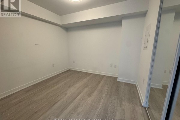 Empty room with white walls, light wood flooring, and a large mirrored closet door. - 326 - 3 Strathgowan Avenue, Toronto