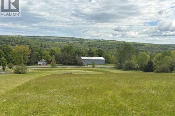 Close-up of a large grey metal barn with an open red-trimmed entrance, next to a smaller shed. - 326 Dorn Ridge Road, Burtts Corner