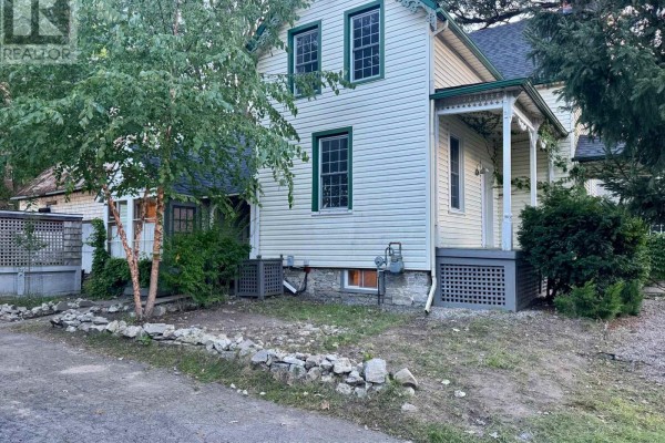 Front exterior view of a cream-colored house with a white fence in the foreground. - 326 Third Street E, Cornwall