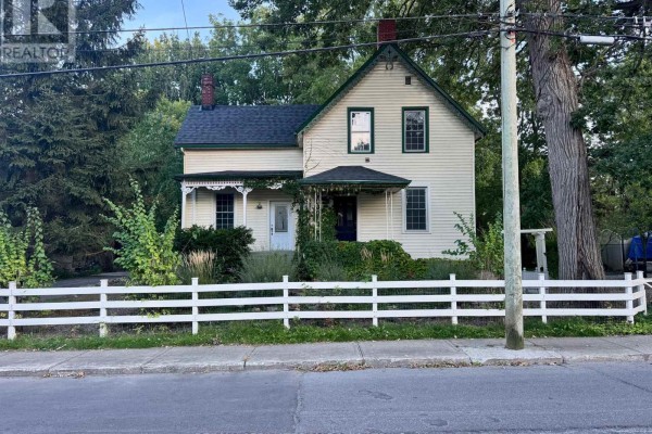 Rear exterior view of the house with a brick chimney, white siding, and a back door. - 326 Third Street E, Cornwall