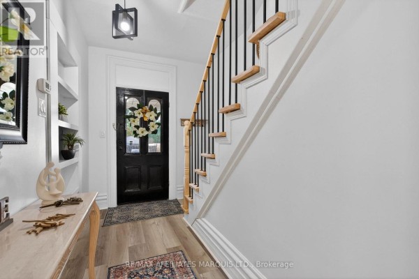 Entrance foyer with a black front door, staircase with wooden banister, and built-in shelving. - 326 Third Street E, Cornwall