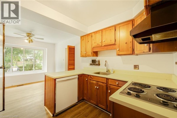 Kitchen with light wood cabinetry, white countertops, a double sink, dishwasher, and a view to the dining area. - 326 Walkers Line, Burlington
