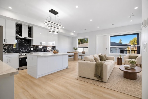 Spacious white kitchen featuring a large island, black marble backsplash, and light wood floors. - 32613 Cherry Avenue, Mission