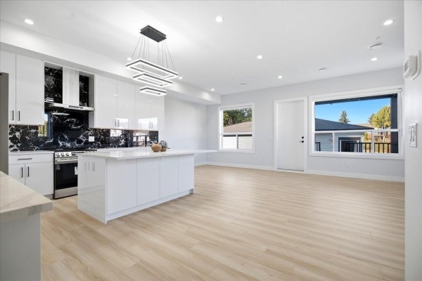 Open concept kitchen and living area with white cabinetry, black backsplash, and large windows. - 32613 Cherry Avenue, Mission