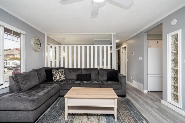 Living room with a gray sectional sofa, light wood coffee table, and gray walls. - 32646 Antelope Avenue, Mission