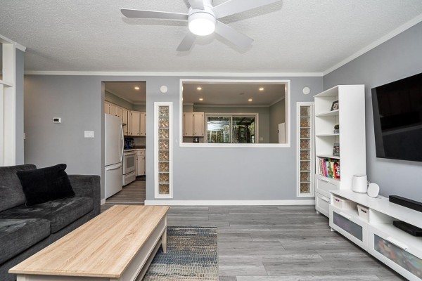 Living room with a gray sectional sofa, entertainment unit, and a view into the kitchen. - 32646 Antelope Avenue, Mission