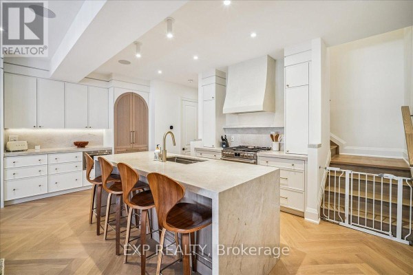 Gourmet kitchen with white cabinetry, stainless steel appliances, and large island with bar stools - 3266 Sixth Line, Oakville